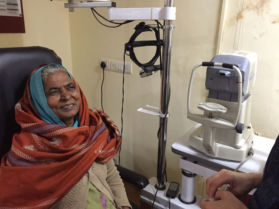 Eine ältere Frau sitzt auf dem Behandlungsstuhl in der Augenklinik. 
