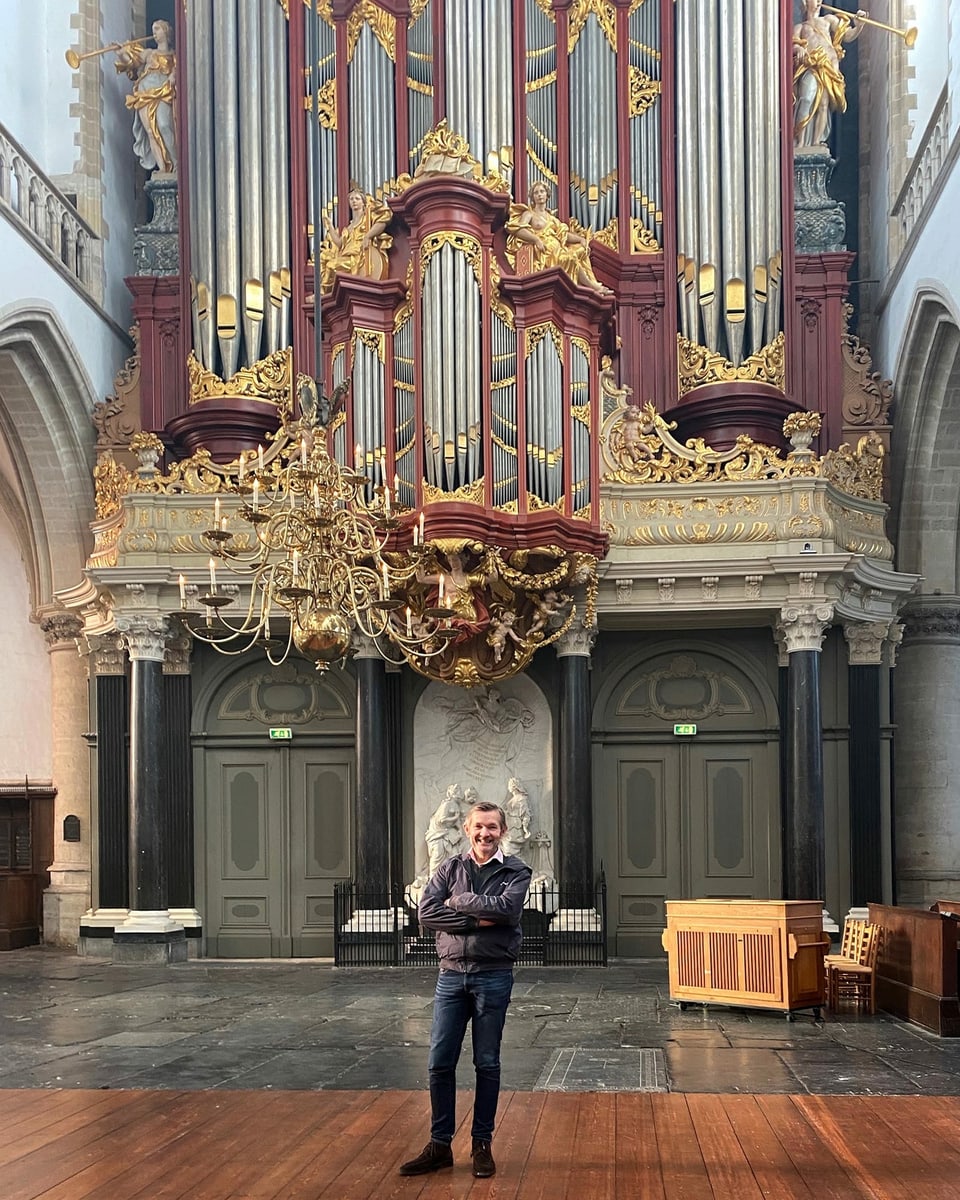 ein Mann steht vor einer imposanten Orgel