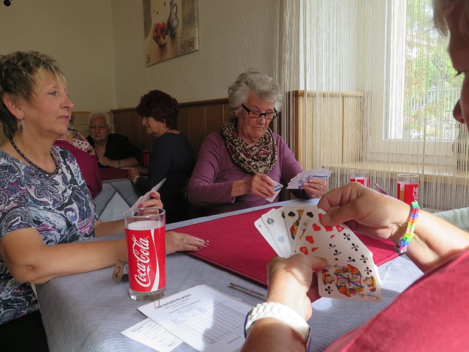 Frauen an einem Tisch in einem Restaurant, Getränke, Jasskarten in den Händen.