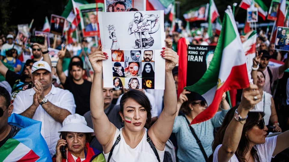 Ein Demonstrationszug in Berlin mit vielen Menschen und vielen iranischen Flaggen.