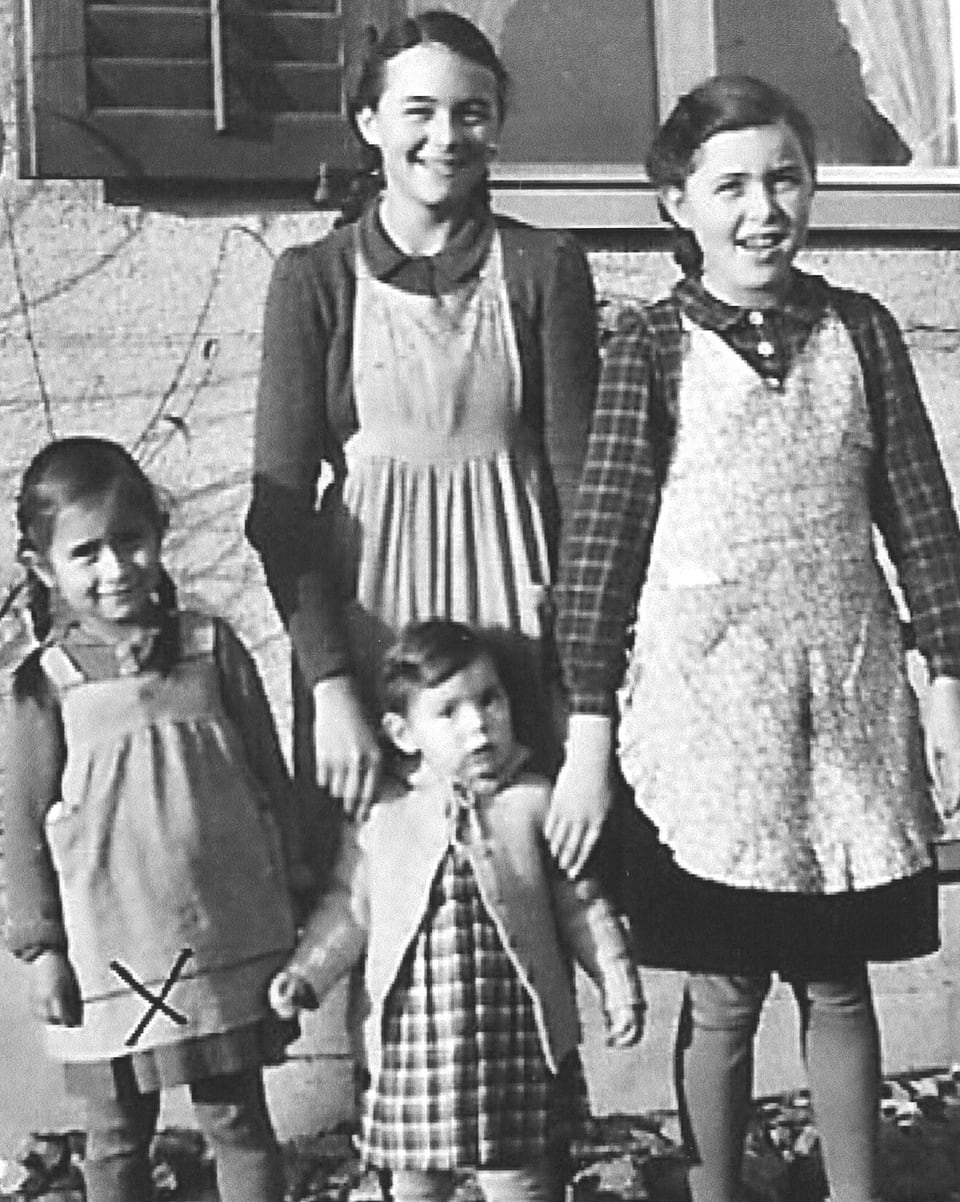 Vier junge Mädchen in bäuerlichen Kleidern mit Schürze und geflochtenen Haaren.