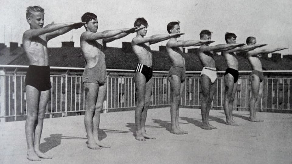 Schwarzweiss-Aufnahme von Jungen in Badehosen bei Trockenübungen.