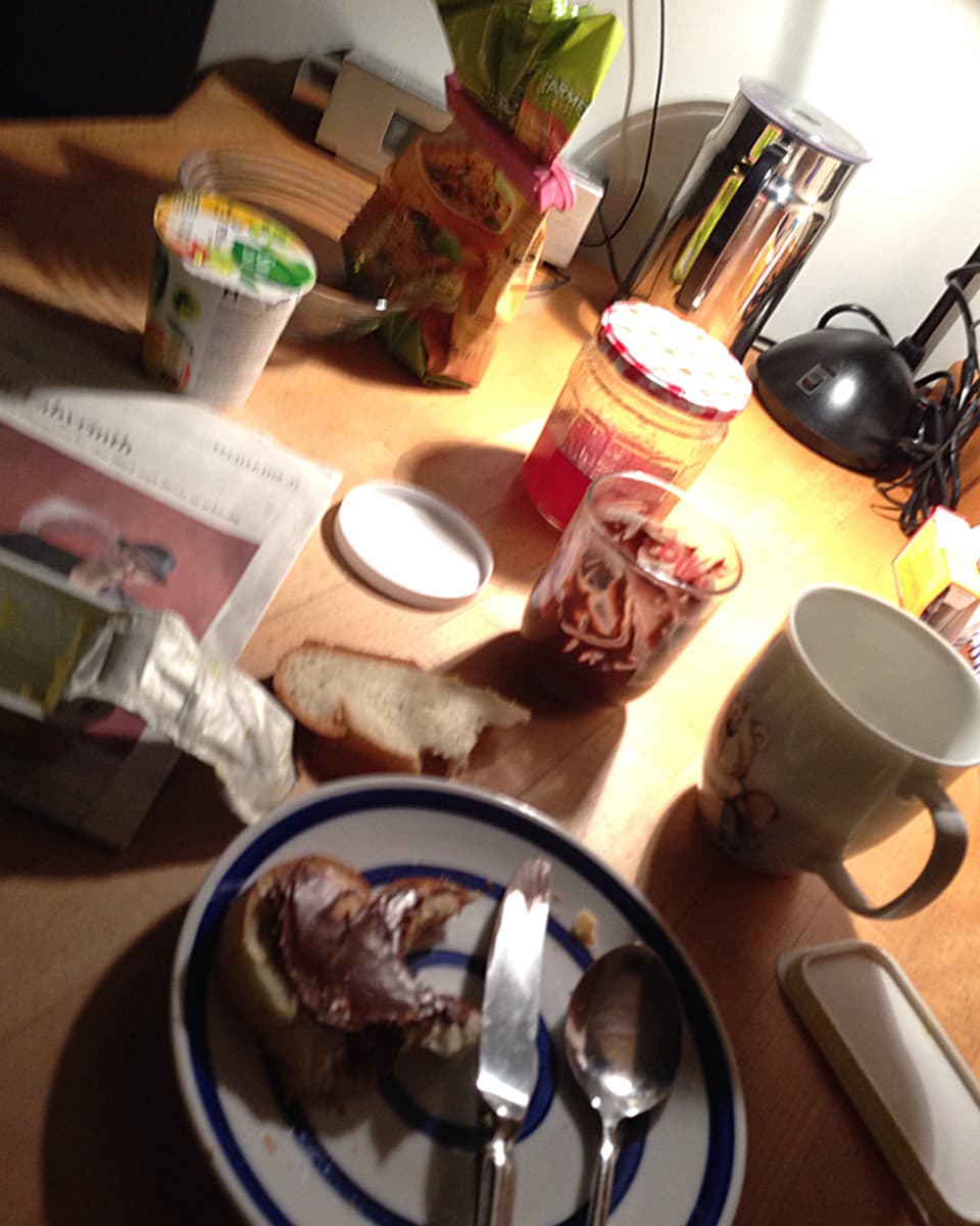 Nutellabrot, Yoghurt, Zeitung; Tasse auf dem Frühstückstisch.