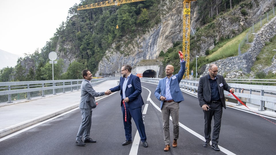Vier Männer freuen sich nach Eröffnung einer Brücke.