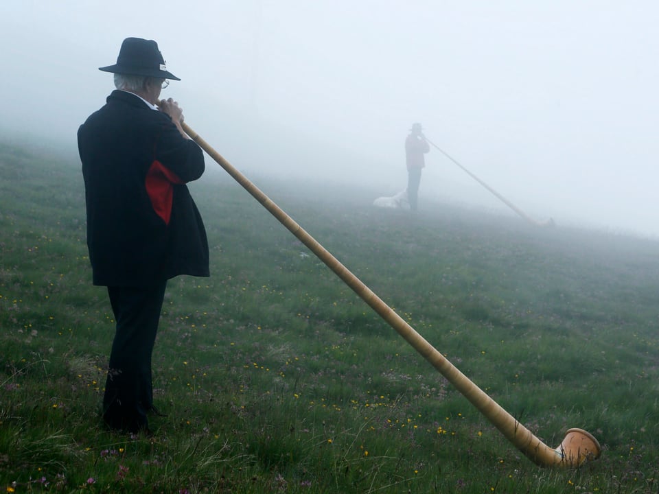 Zwei Alphornbläser am letzten Tag des Festivals in Lac de Tracouet in der Nähe von Nendaz im Wallis. Es lag zunächst noch dichter Nebel über der Region.