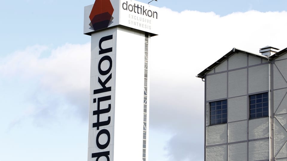 Logo von Dottikon ES neben einem Fabrikgebäude