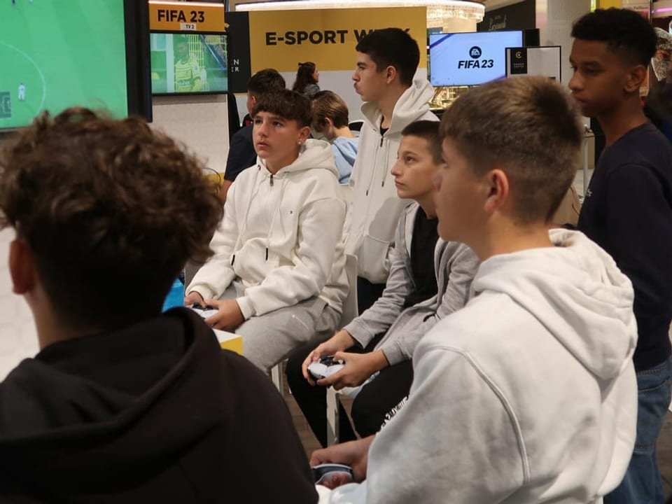 Junge Gamer spielen in einem Shoppingcenter Fifa.