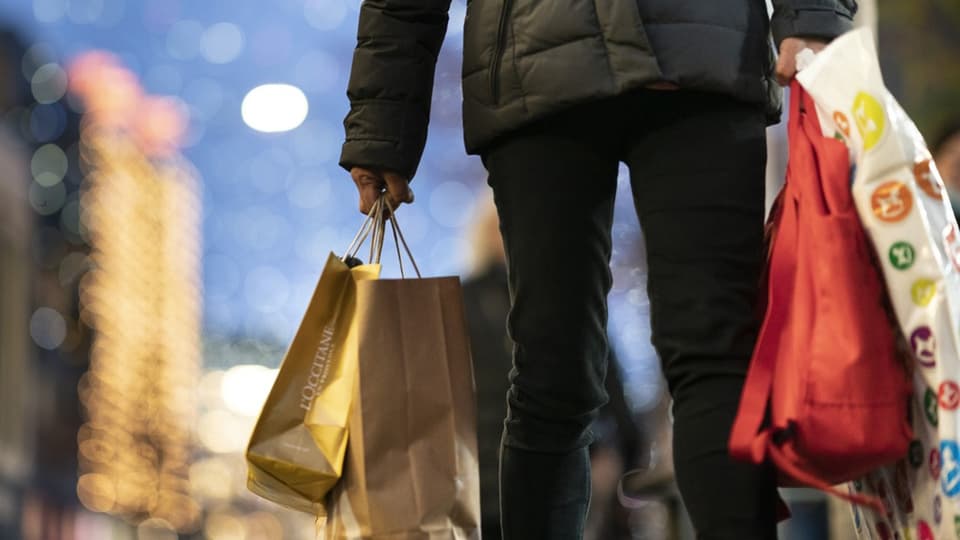 Eine Person, die mehrere Einkaufstaschen verschiedener Läden in den Händen hält