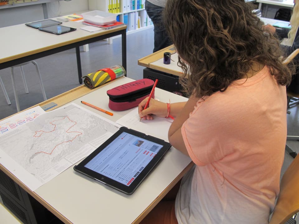 Schülerin an Pult mit iPad und Schweizer Karte
