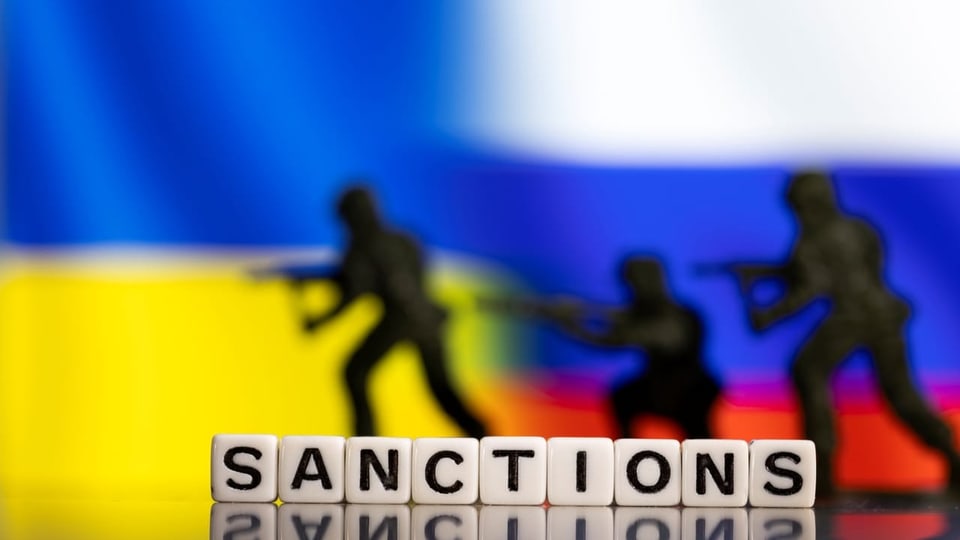 Scrabble-Würfel bilden das Wort «Sanctions» vor den Flaggen von Russland und der Ukraine.