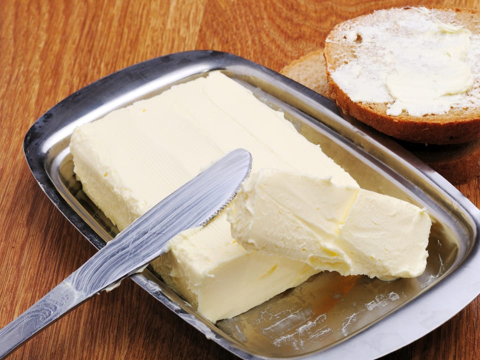 Margarine mit einem Messer und einem Stück Brot.