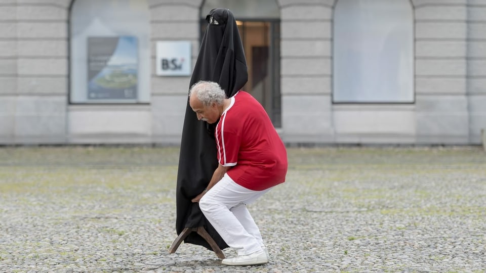 Mann mit Puppe, die eine Burka trägt.