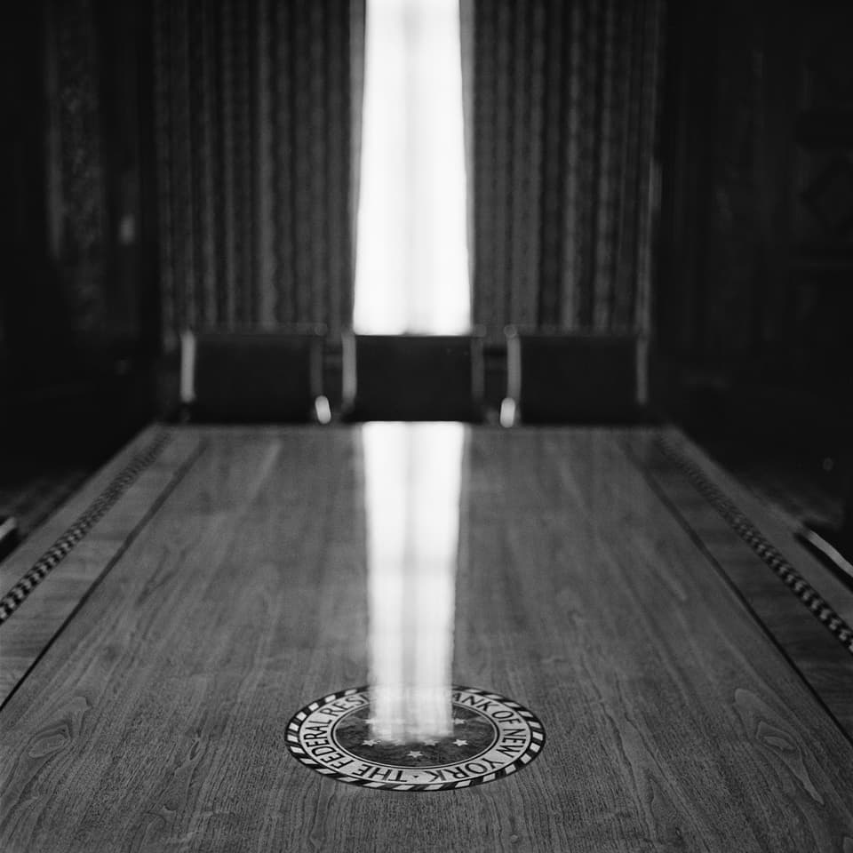 Wooden meeting table with emblem of the bank. Light falls through a window onto the table and creates a reflection