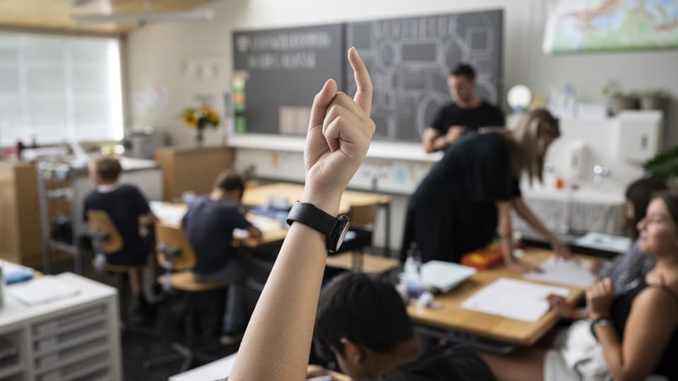 Ein Schüler streckt die Hand während der Schulstunde empor.