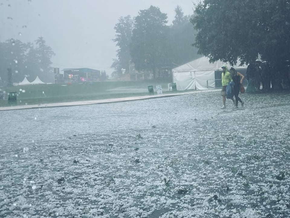 Starker Hagel und zwei Personen, die sich Schutz suchen.