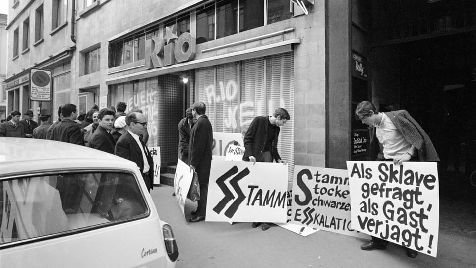 eine schwarz-weiss Fotografie von Demonstrierenden mit Plakaten