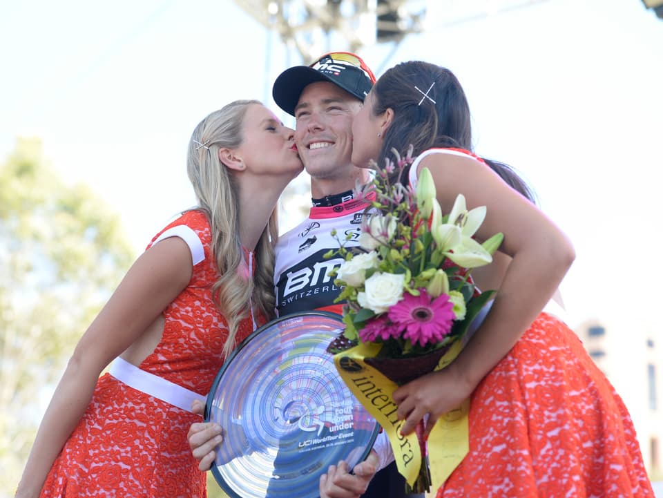 Rohan Dennis wird nach dem Gesamtsieg bei der Tour Down Under von zwei Ehrendamen auf die Wange geküsst.