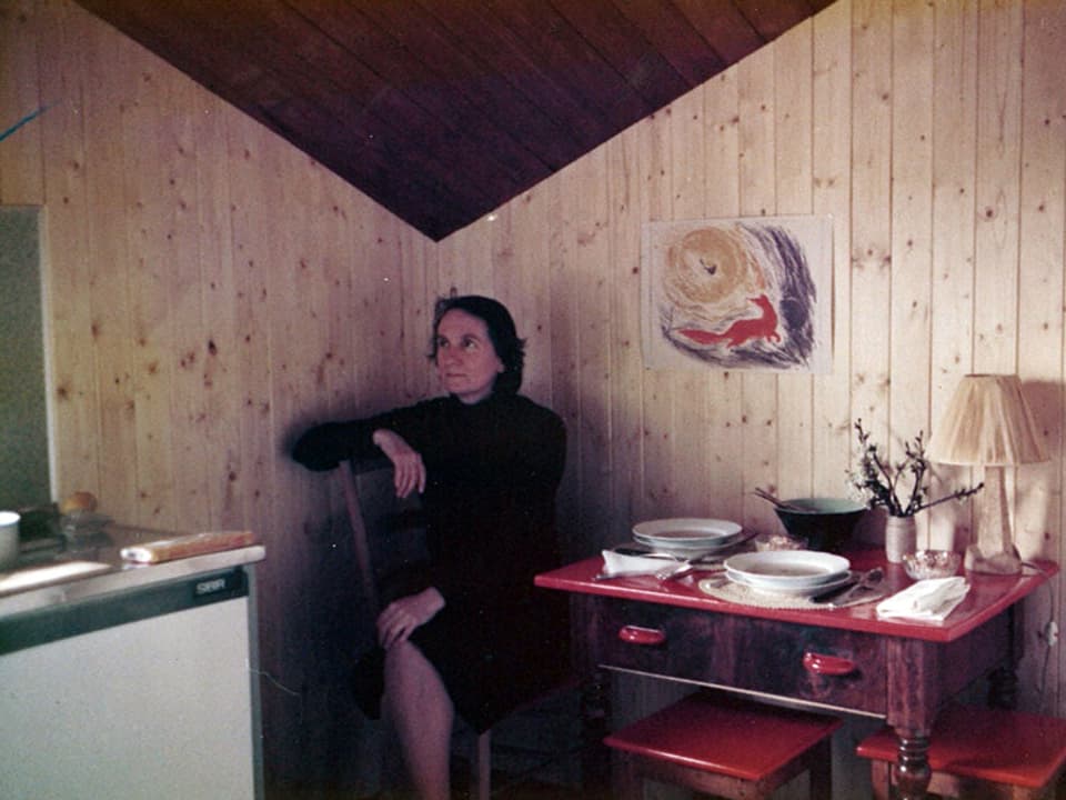 Christine Custer sitzt an einem roten Küchentisch, auf dem zwei Teller Suppe stehen.