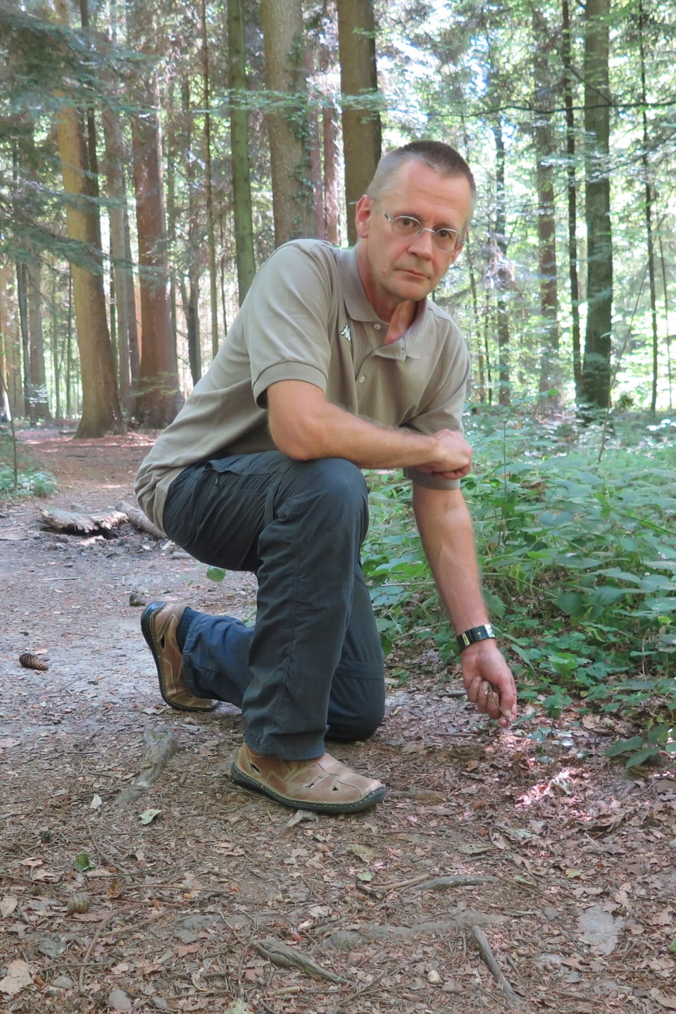 Mann kniend auf Waldboden