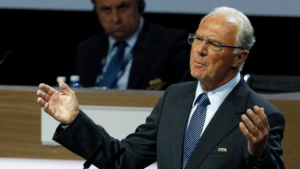 Franz Beckenbauer an einem Rednerpult.