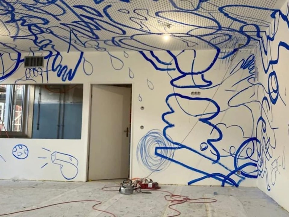 Werkzeuge liegen auf dem Boden, an die weisse Wand sind überall blaue Linie gemalt. In der Mitte steht ein Tür halb auf.