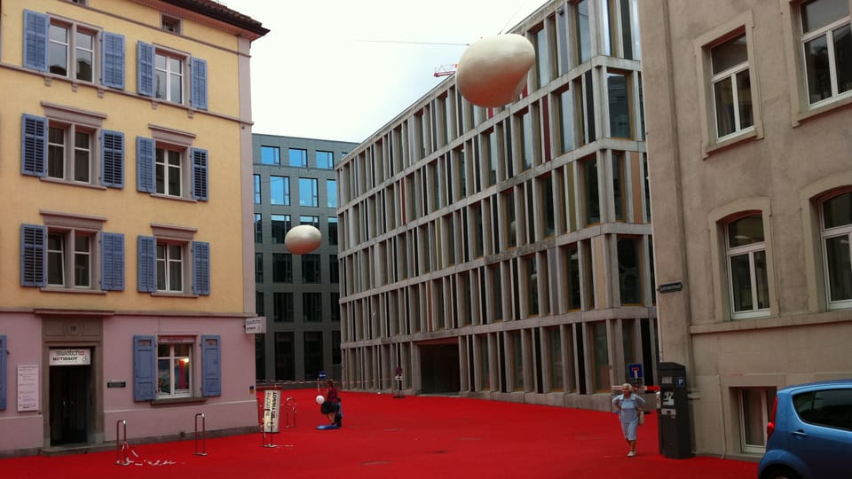 Ein roter Boden mit modernen und älteren Gebäuden rundherum.