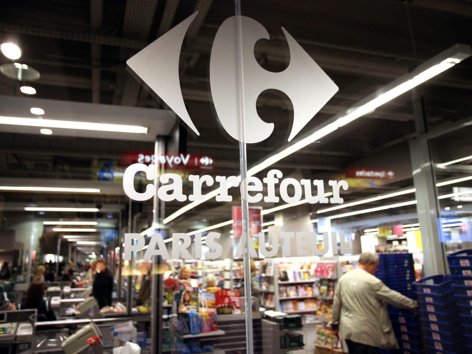 Das Carrefour Logo an einem Fenster.