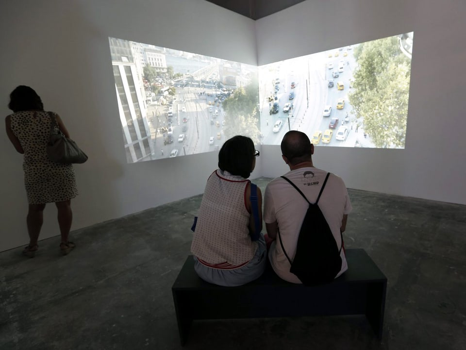 Zwei Besucher sitzen vor einer Video-Projektion.