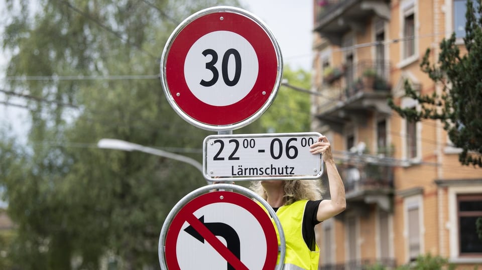 Frau montiert Schild für Tempo-30-Zone in Zürich.
