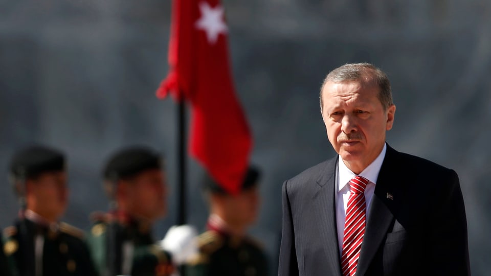 Der türkische Präsident Recep Tayyip Erdogan im Porträt vor der türkischen Flagge im Hintergrund.
