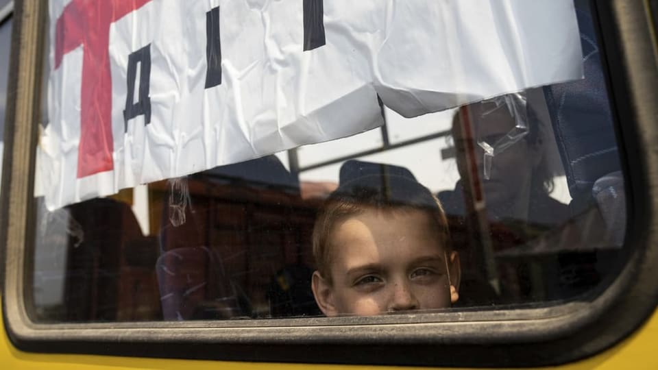 Junge blickt aus einem Evakuierungsbus.