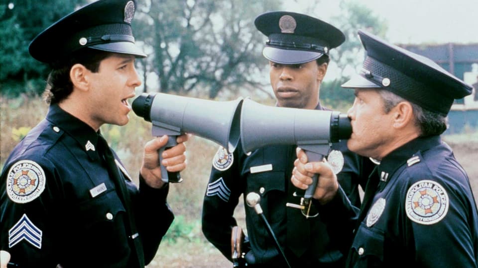 Filmszene Zwei Polizisten sprechen aus nächster Distanz durch zwei Megaphone miteinander