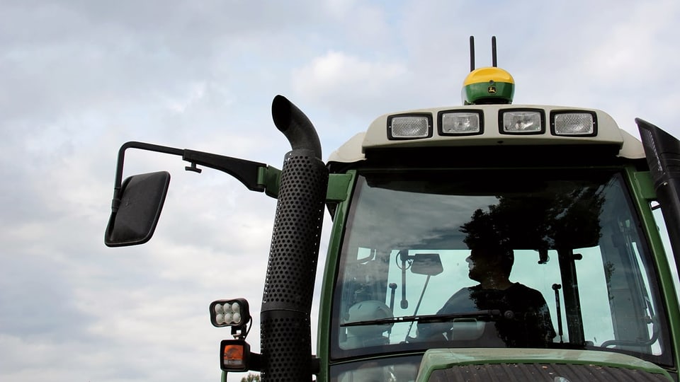 Ein Traktor, auf dem Dach ist eine grün-gelbe GPS-Box mit zwei Antennen montiert.