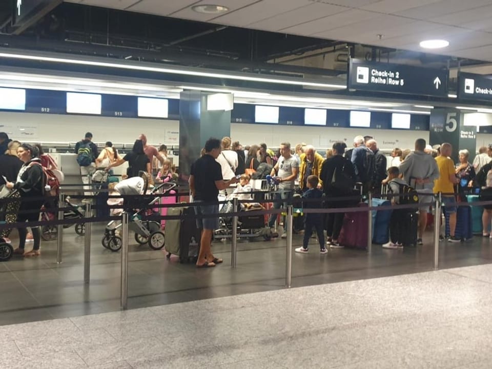 Menschen stehen am Flughafen Zürich fürs Check-in an.