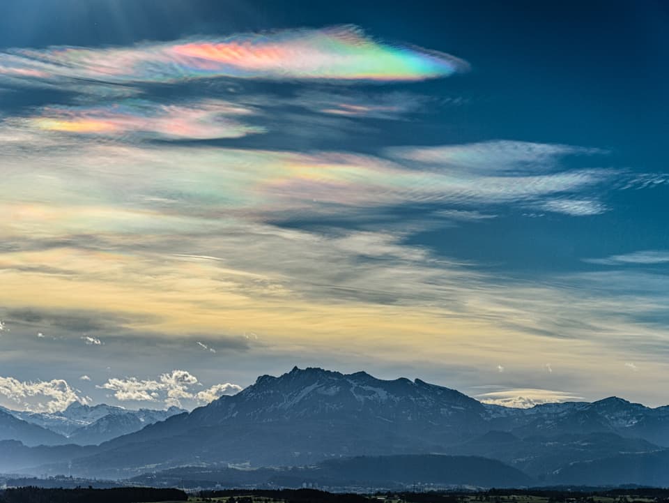 Im Vordergrund die Berge, darüber Wolken auf verschiedenen Schichten. Inkl. den farbig leuchtenden Wolken.