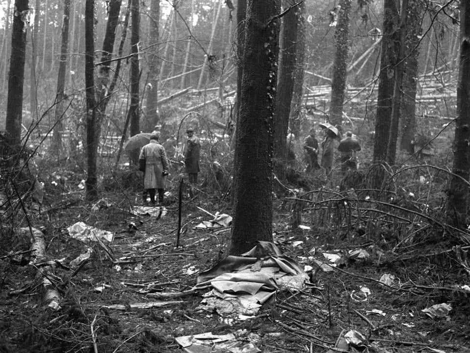 Schwarzweissaufnahme von 1970. Männer begutachten die Trümmer im Wald. 