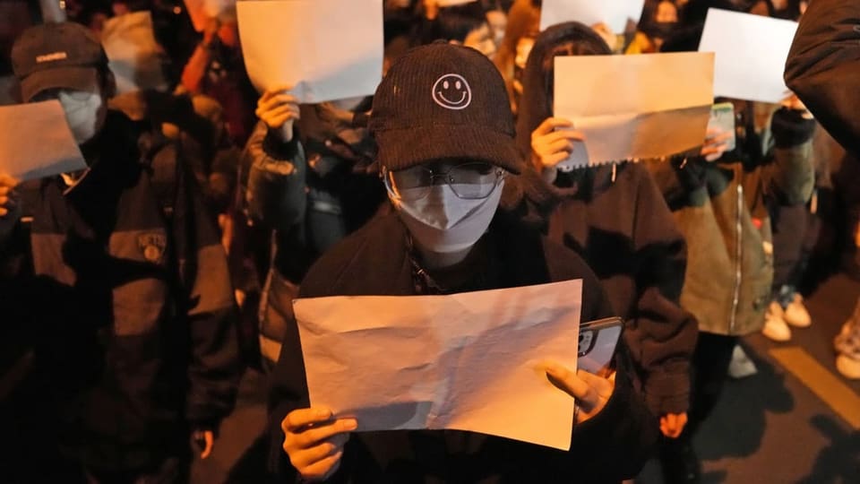 Demonstranten halten ein weisses Papier in die Höhe.