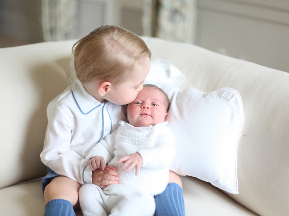 Prinz George hält seine kleine Schwester Charlotte im Arm und gibt ihr einen zärtlichen Kuss auf die Stirn