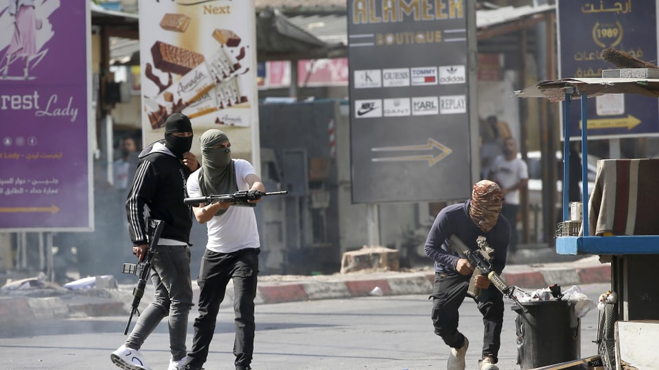 Drei Männer mit Gewehren und Sturmmasken in den Strassen Dschenins