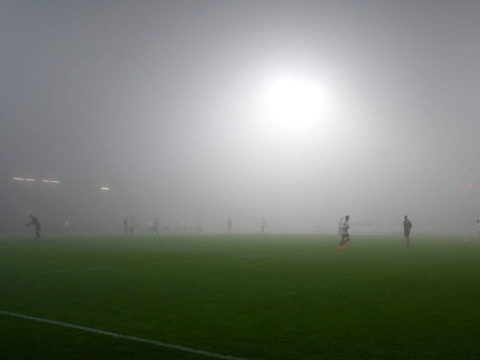 Dunstige Sache Dichter Nebel liegt auf dem Fussballfeld.