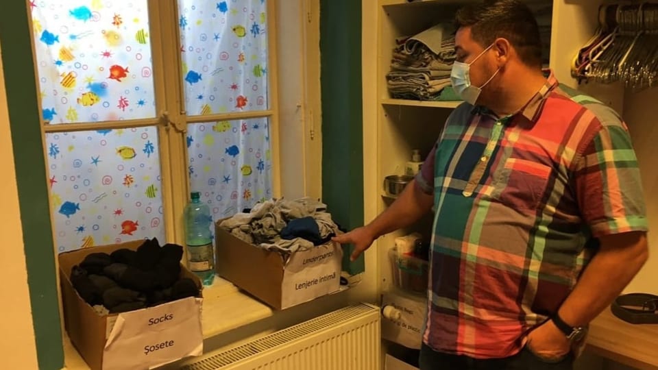 Ein Mann mit Maske, vor ihm zwei Kartons mit Unterwäsche und Socken.