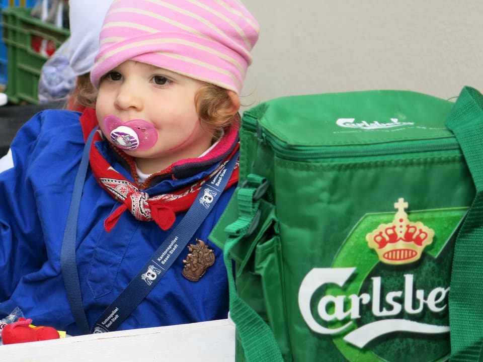 Kind mit Nuggi, daneben Carlsberg-Kühltasche