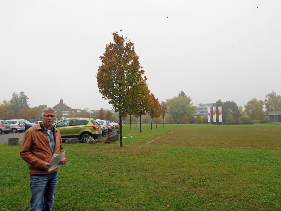 Ernst Zülle steht links im Bild, rechts eine grüne grosse Wiese