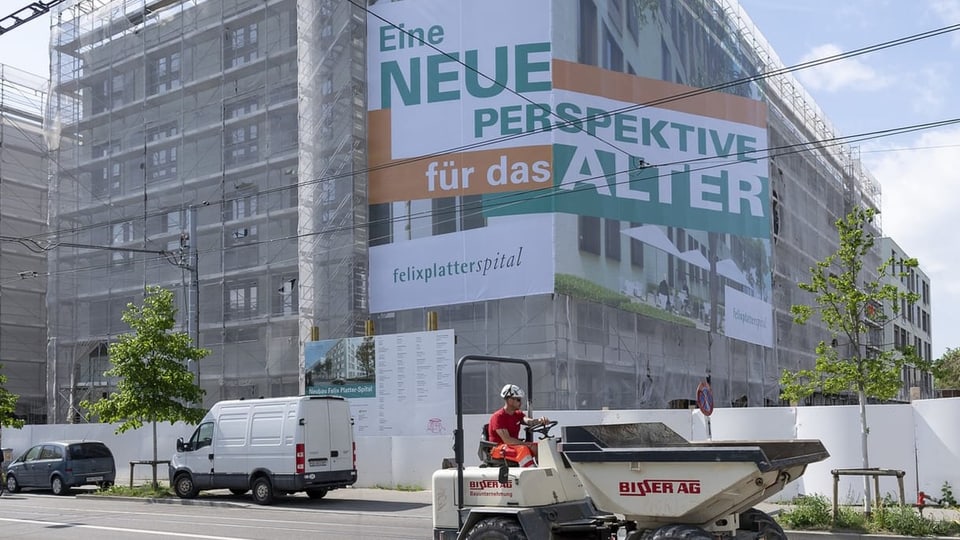 Haus im Bau von aussen. Grosses Plakat ist dran: «Eine neue Perspektive für das Alter.».