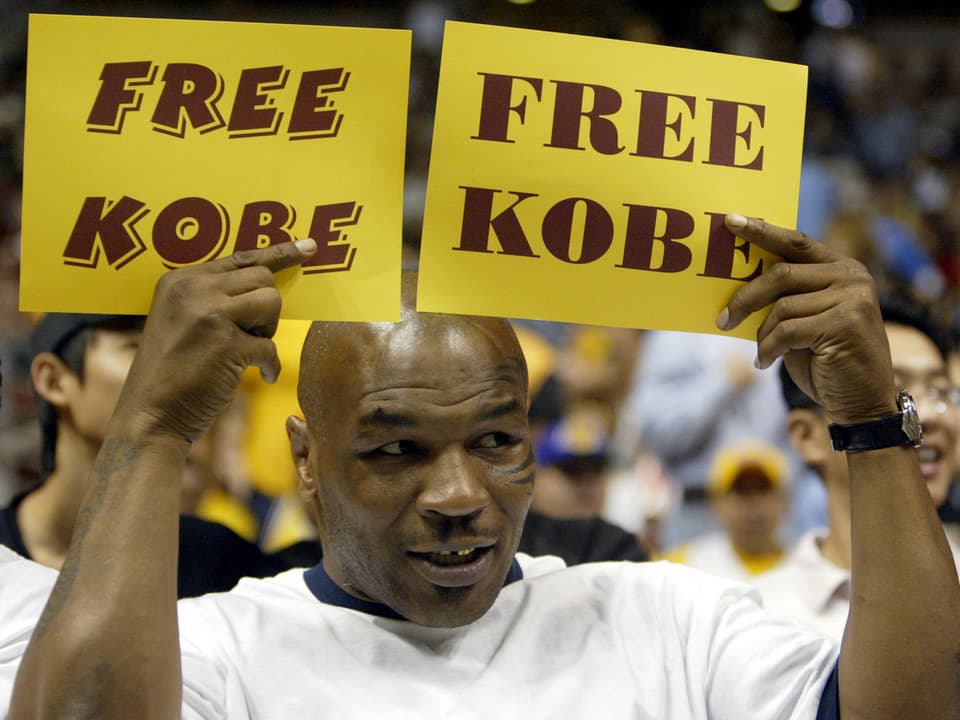 Boxstar Mike Tyson hält zwei Schilder mit der Aufschrift "Free Kobe" in die Luft.