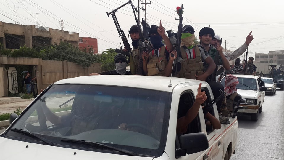 Kämpfer des Islamischen Staats in Siegerpose auf einem Pick-up-Fahrzeug.
