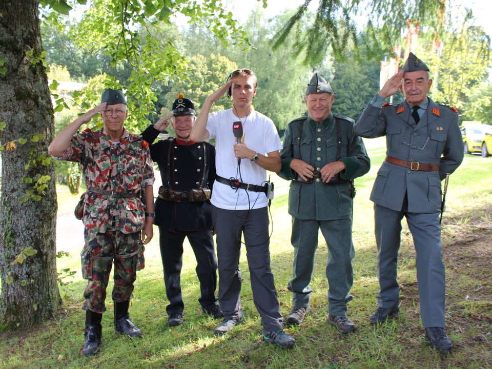 Reto Scherrer salutiert zusammen mit Soldaten in alter Militäruniform.