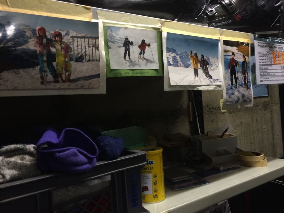 Alte Fotos von Menschen beim Skifahren hängen an der Wand.