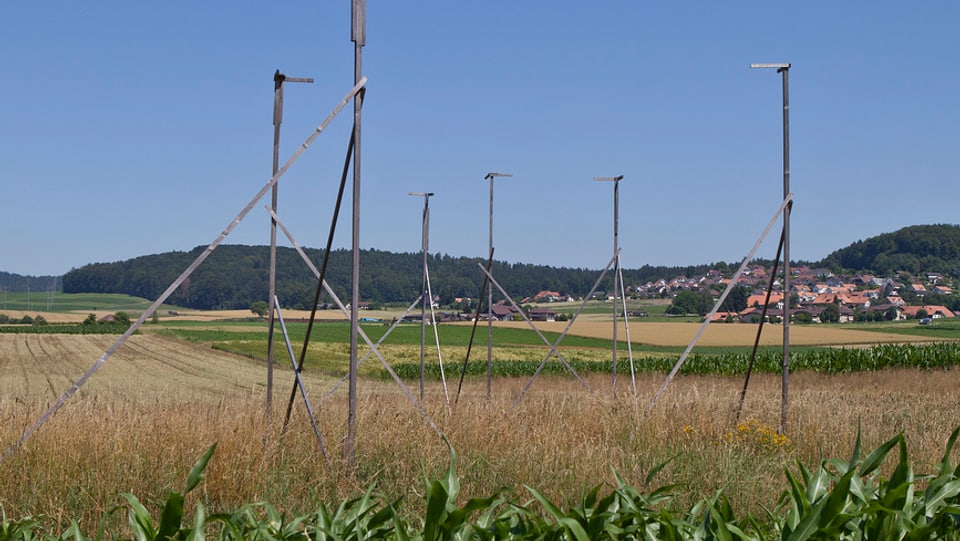 Baugespann auf Feld, im Hintergrund Dorf