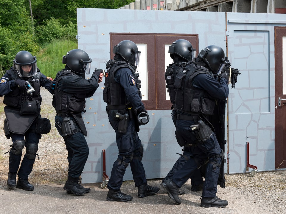 Polizisten der Sondereinheit in Vollmontur vor einer Hauswand.